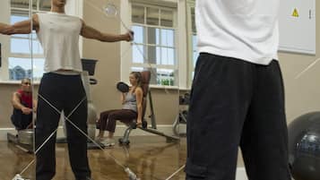 A gym with exercise equipment, a large mirror, and a view of buildings outside.