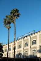 A building with a sign reading "Victoria & Alfred Hotel" and tall palm trees in front.
