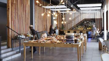 A restaurant with a long wooden counter displaying various food items and a bar area in the background.