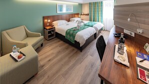 Una habitación de hotel con cama, escritorio, silla, sofá y mesita de noche.