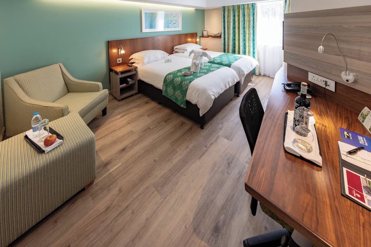 A hotel room with a bed, a desk, a chair, a sofa, and a nightstand.