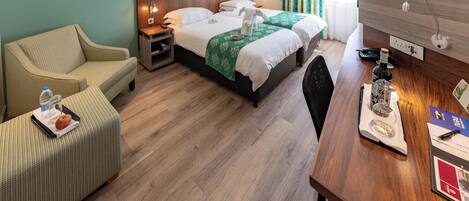A hotel room with a bed, a desk, a chair, a sofa, and a nightstand.