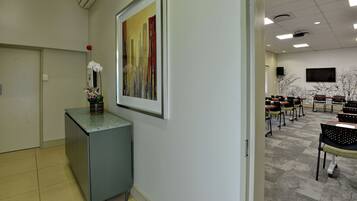 A reception area with a desk, a framed painting, and a flower arrangement.
