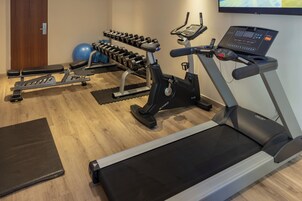 Uma academia com esteira, halteres e bolas de exercício.