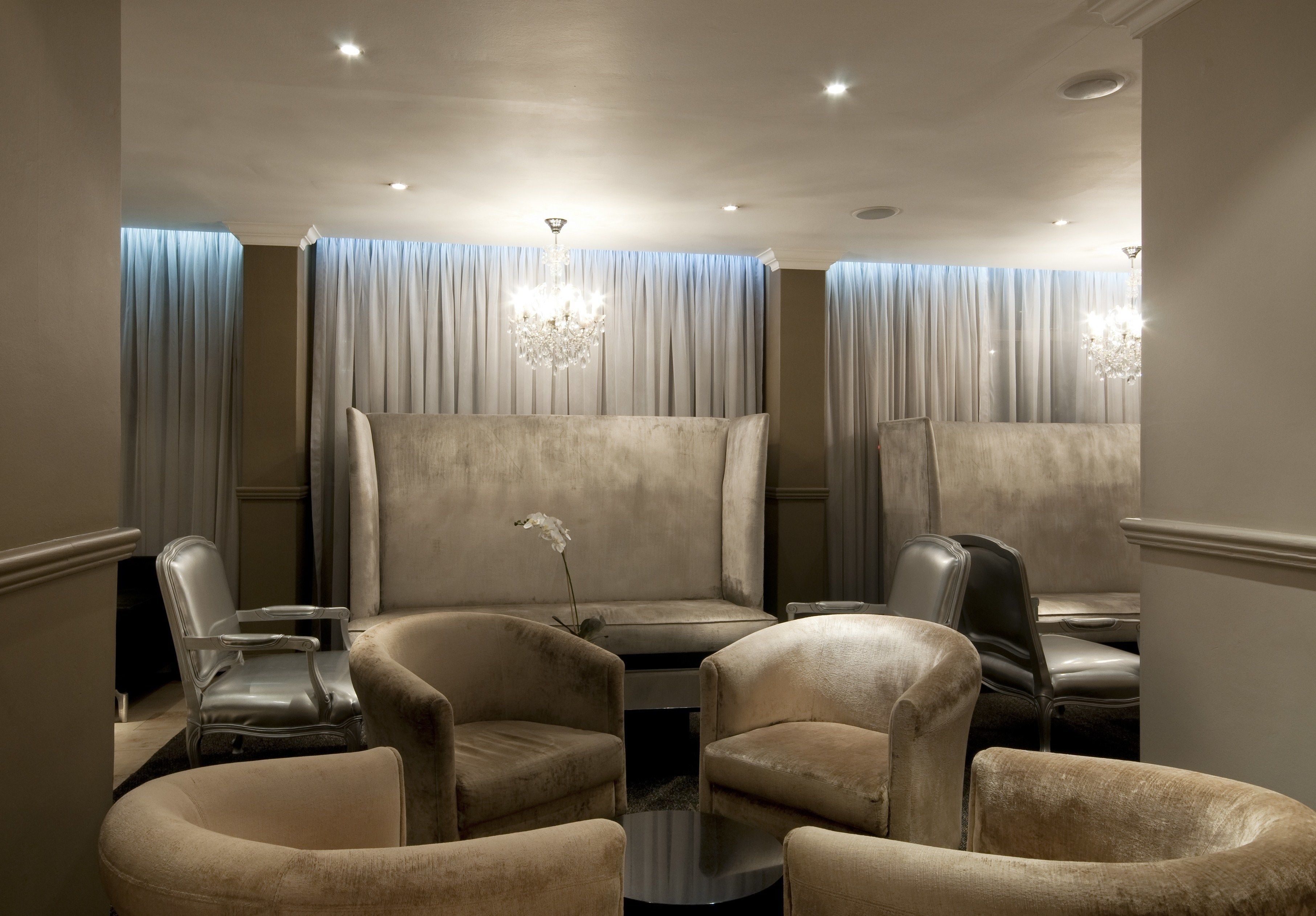 A room with a large, plush sofa, several armchairs, a small coffee table, and a chandelier.