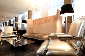 Um lobby de hotel moderno com poltronas de couro, um sofá e um lustre.