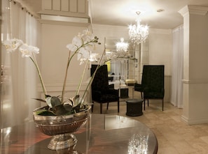 Uma sala de jantar com uma mesa espelhada, um arranjo de orquídeas brancas e um candelabro.