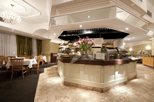 A well-lit, elegant dining area with a central island, wooden chairs, and a chandelier.