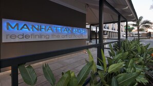 La entrada de un hotel con un letrero que dice "MANHATTAN HOTEL, reinventando el arte de la hospitalidad."