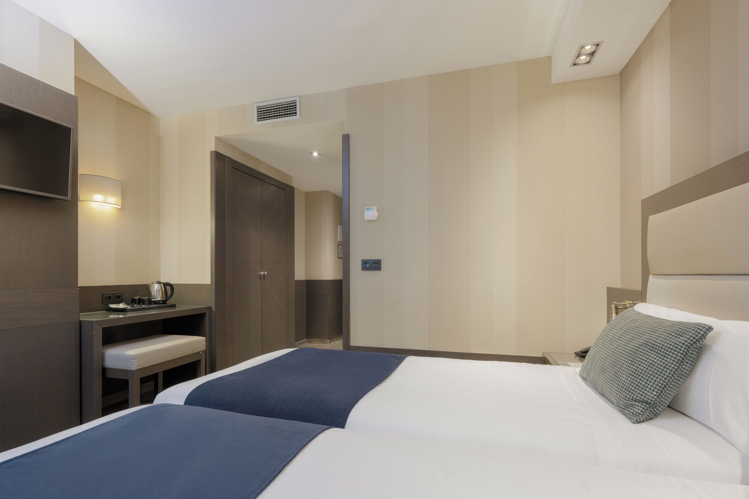 A hotel room with a large bed, bedside tables, a desk, and a television.
