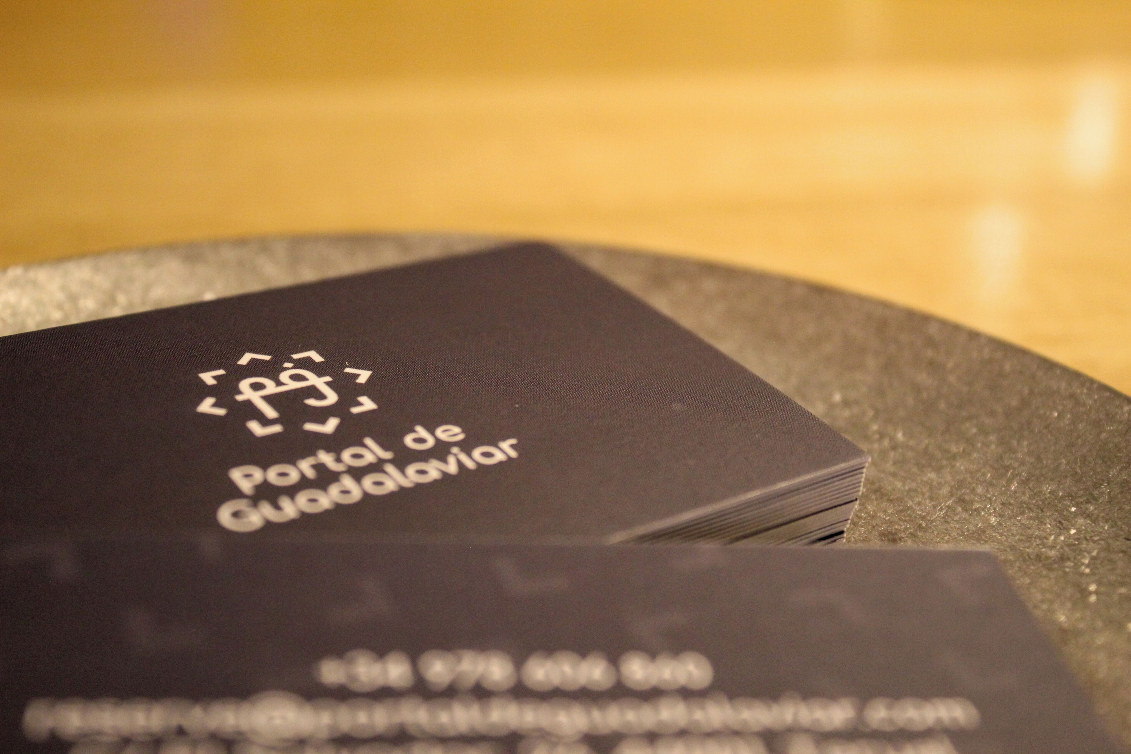 A stack of black business cards with the text 'Portal de Guadalarva' and a phone number.