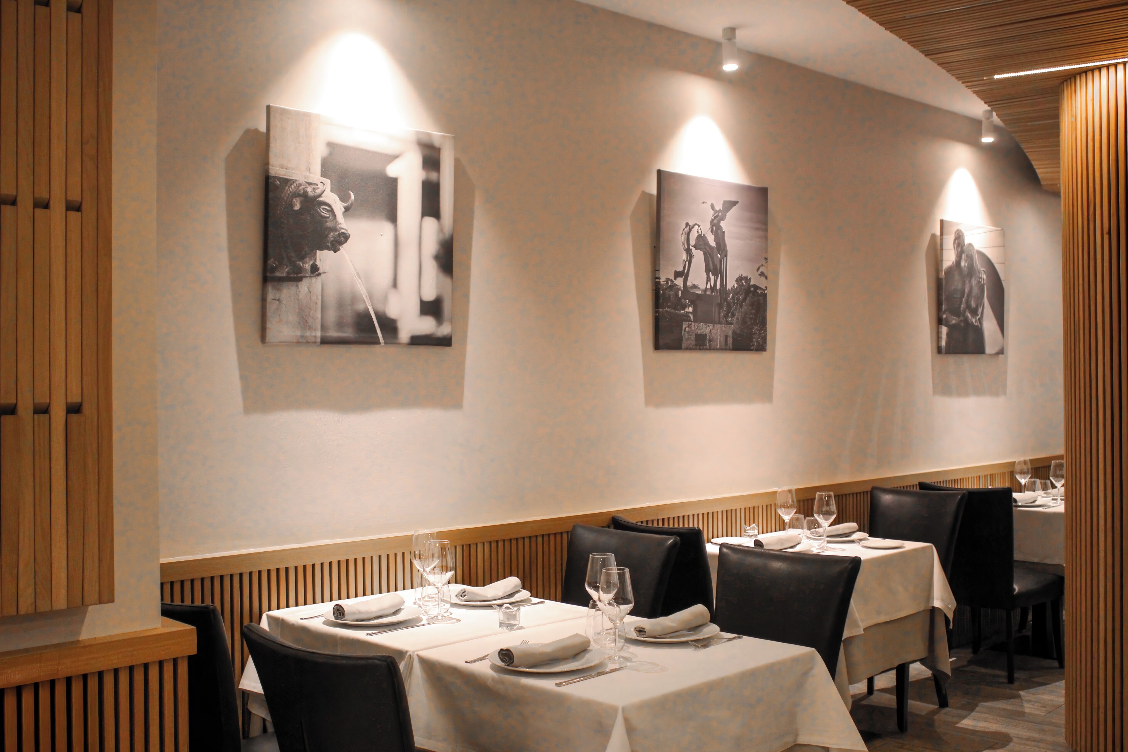 Un restaurante con mesas dispuestas para comer, obras de arte enmarcadas en las paredes y paneles de madera.