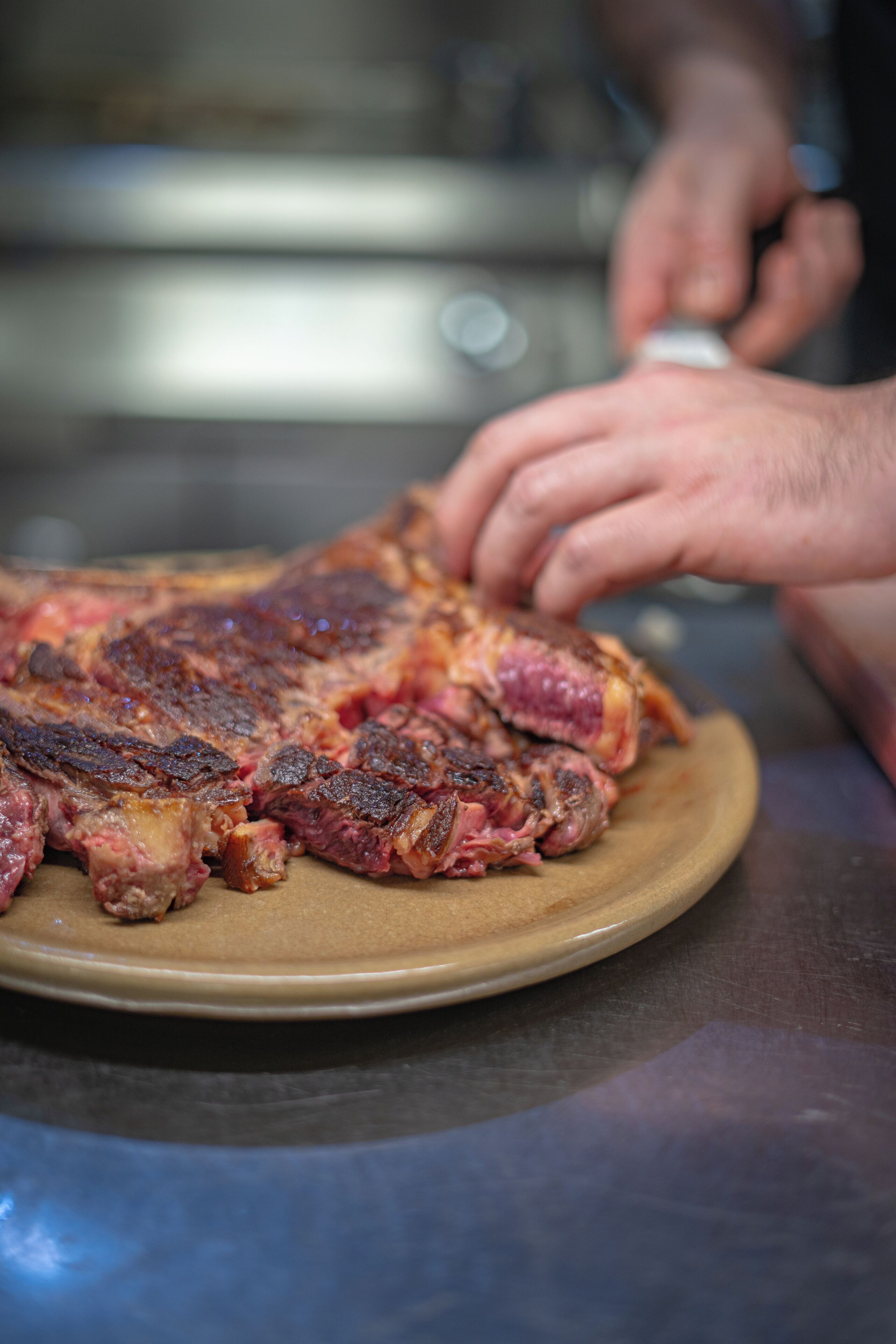 Une vue rapprochée d’un steak cuit sur une assiette, avec une personne en arrière-plan.