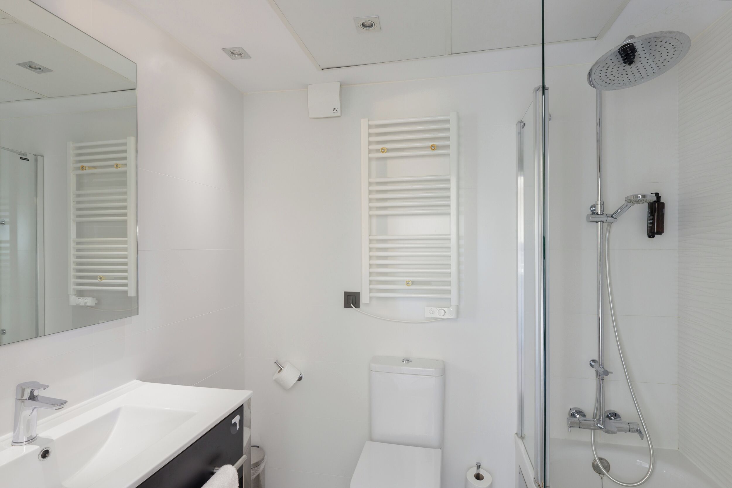 Een moderne badkamer met een wit wastafel, toilet en douche.