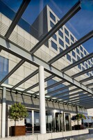 Um edifício moderno com fachada de vidro e estrutura metálica geométrica.