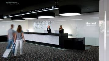 Un mostrador de recepción moderno con un cartel que dice "BOARDING DESK" y "Barceló HOTELS & RESORTS".