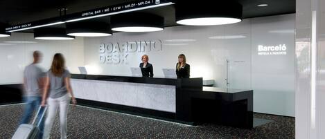 Ein moderner Empfangstresen mit einem Schild, auf dem “BOARDING DESK” und “Barceló HOTELS & RESORTS” stehen.
