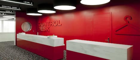 A control desk area with directional signs, a red wall, and a hanging rack.