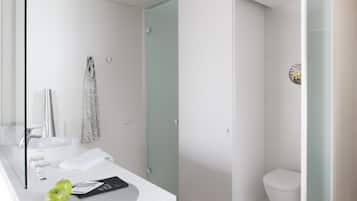 A modern bathroom with a white sink, a glass shower enclosure, and a toilet.