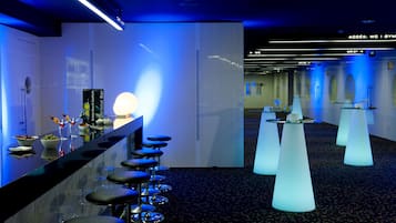 Un moderno vestíbulo de hotel con zona de bar, con taburetes y mostrador.