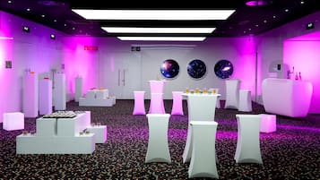 A modern hotel lobby with white furniture, a central bar area, and three wall-mounted galaxy-themed decorations.