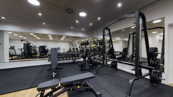 Un gimnasio moderno con diverso equipo de ejercicios, una banca y un espejo grande.