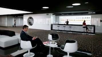 A modern lounge area with a bar, seating, and a large mirror.