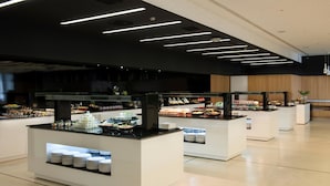 Un moderno montaje de buffet con varias estaciones de comida, cada una con una vitrina de cristal y una variedad de platos.