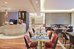 Un hall d’hôtel moderne comprenant un comptoir d’accueil, un espace salon et un mur décoratif.