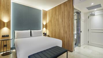 Een moderne hotelkamer met een groot bed, houten paneelwanden en een klein nachtkastje met een lamp.