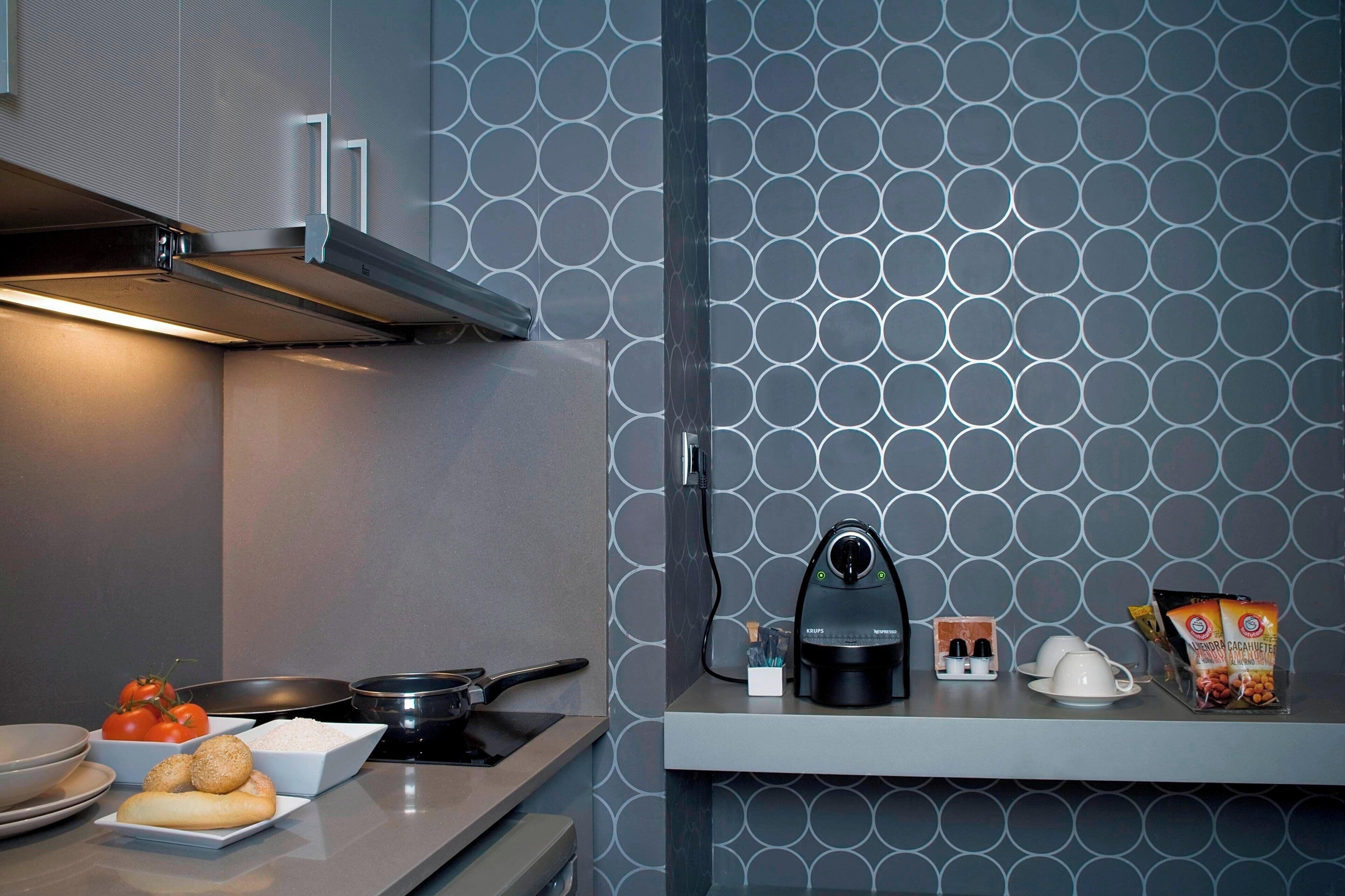 Uma cozinha moderna com painel decorado, fogão embutido e máquina de café no balcão.