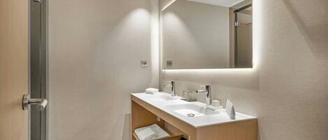 Un baño moderno con tocador doble, espejo y perchero.
