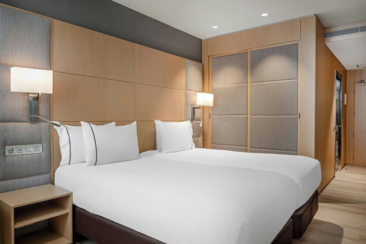 A large bed with white linens, wooden headboard, and bedside tables with lamps.