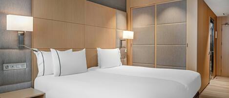 A large bed with white linens, wooden headboard, and bedside tables with lamps.