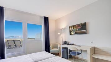Habitación de hotel con cama, escritorio, silla y vistas al exterior.