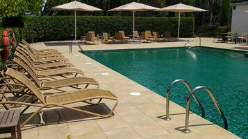 Una piscina al aire libre, sombrillas, tumbonas