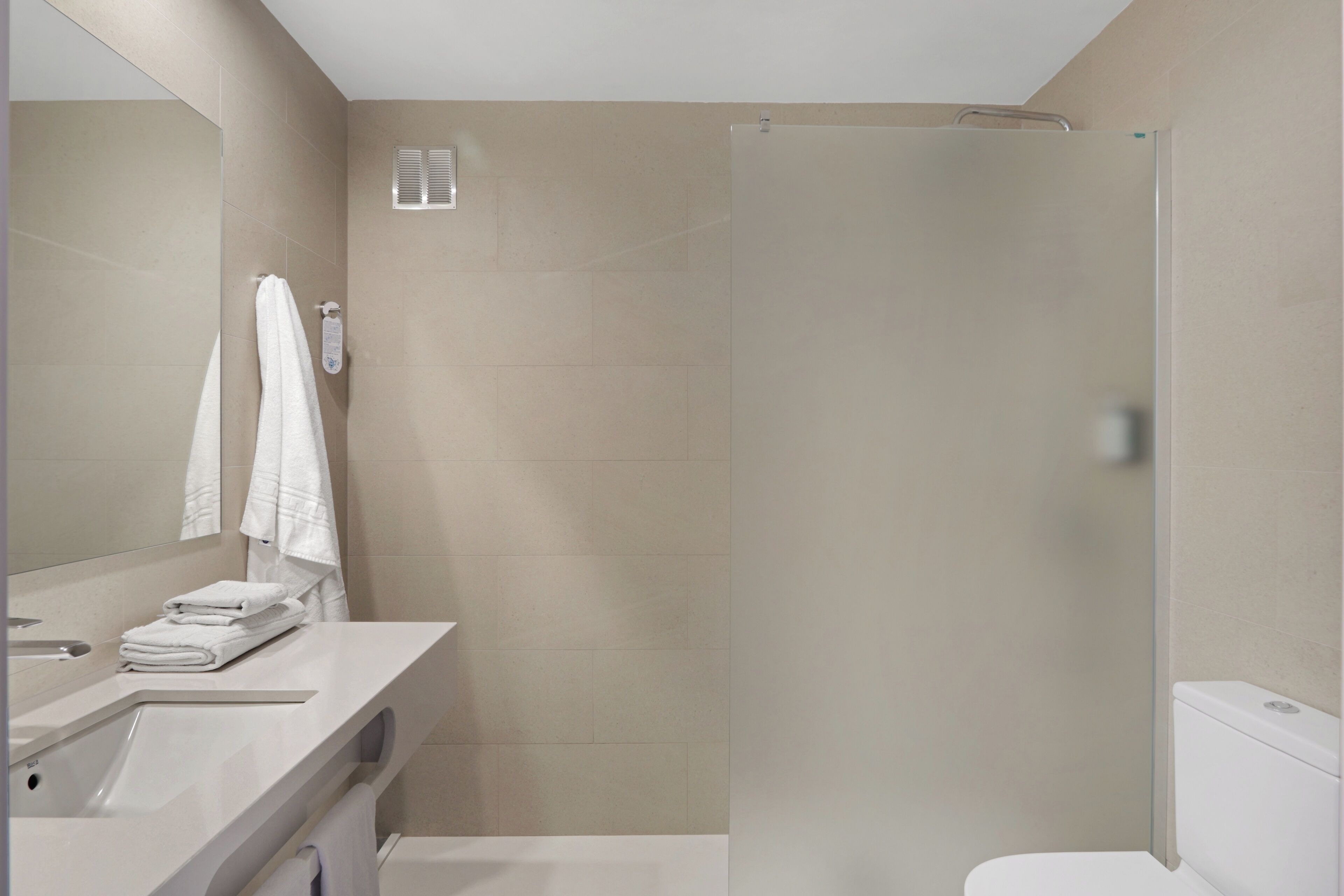 A modern bathroom with a shower, toilet, and sink.