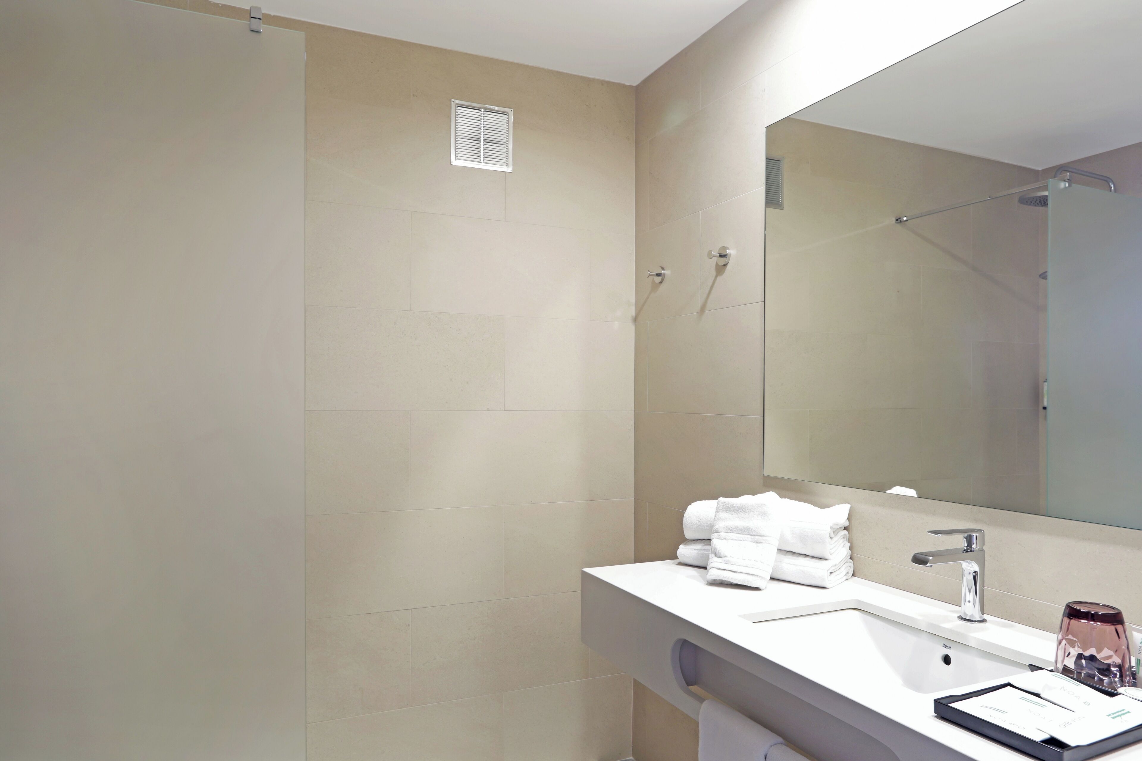A modern bathroom with a shower, a sink, and a large mirror.