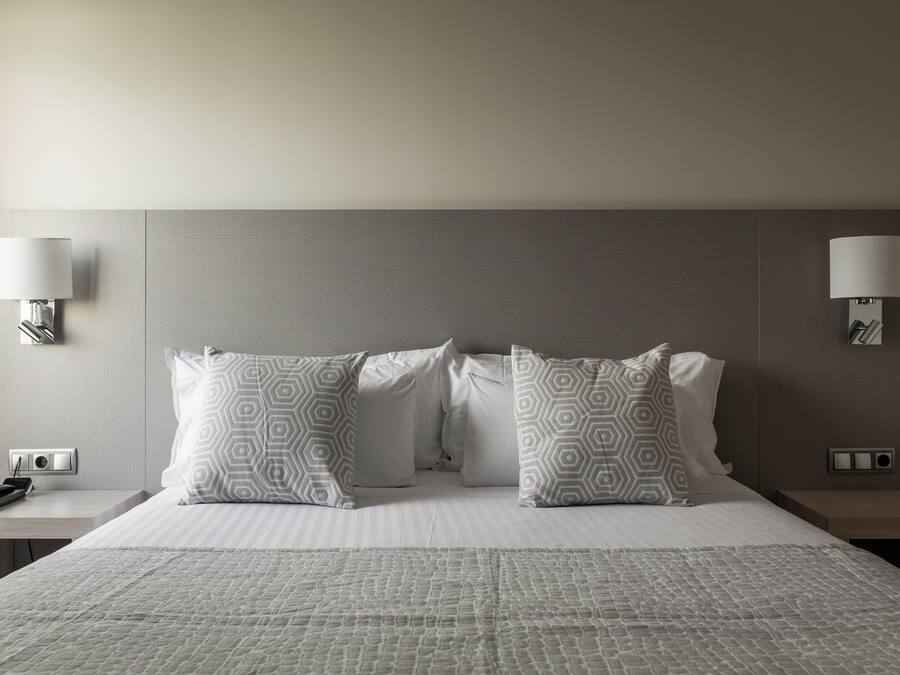 A hotel room with a large bed, two bedside tables, a telephone, and two wall-mounted lamps.