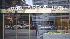 The exterior of the Hotel Abbot Hotel with large glass windows reflecting the street and parked cars. - Hotel Abbot (Barcelona)