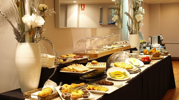 A buffet with various food items, including bread, pastries, and fruits. - Hotel Abbot (Barcelona)