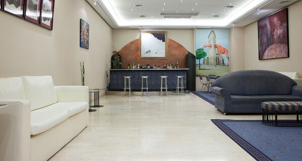 A hotel lobby with a bar area, seating arrangements, and artwork on the walls. - NH Bilbao Deusto (Bilbao)