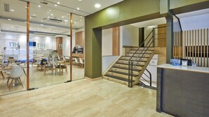 A hotel lobby with a staircase, seating area, and reception desk. - NH Bilbao Deusto (Bilbao)