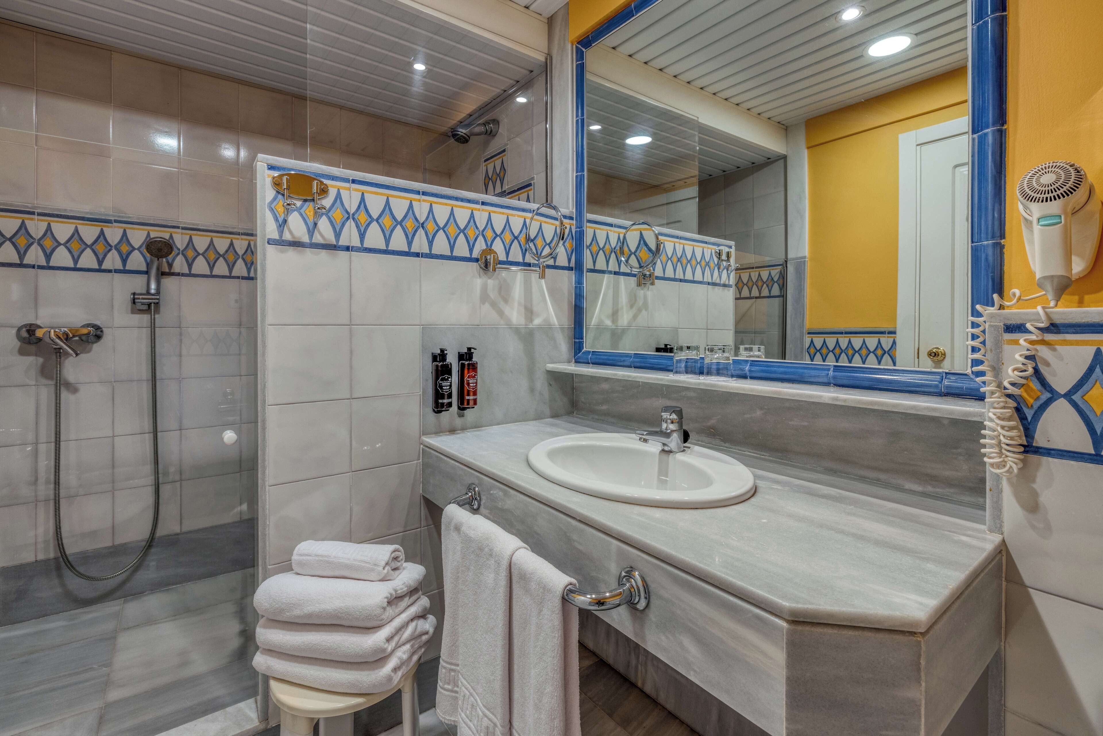 Un baño con ducha, lavamanos y un espejo grande.