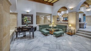 A spacious lobby with a grand piano, green sofas, and a marble floor. - AZZ Guadacorte Campo de Gibraltar (Los Barrios)