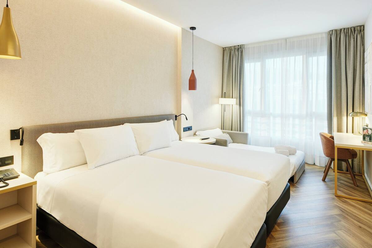A hotel room with a large bed, bedside tables, a desk, and a chair.