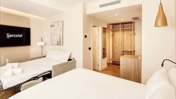 Una habitación de hotel con cama, televisión, un cuadro y un vestidor.
