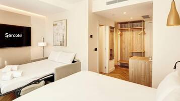 Una habitación de hotel con cama, televisor, mesita de noche, lámpara y armario.