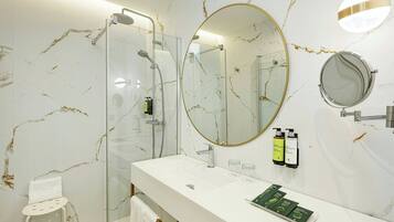 Un bagno moderno con doccia vetrata, un ampio specchio e un mobile lavabo bianco.