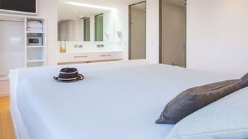 Une chambre à coucher moderne avec un grand lit, une armoire, une coiffeuse avec un miroir et un téléviseur fixé au mur.